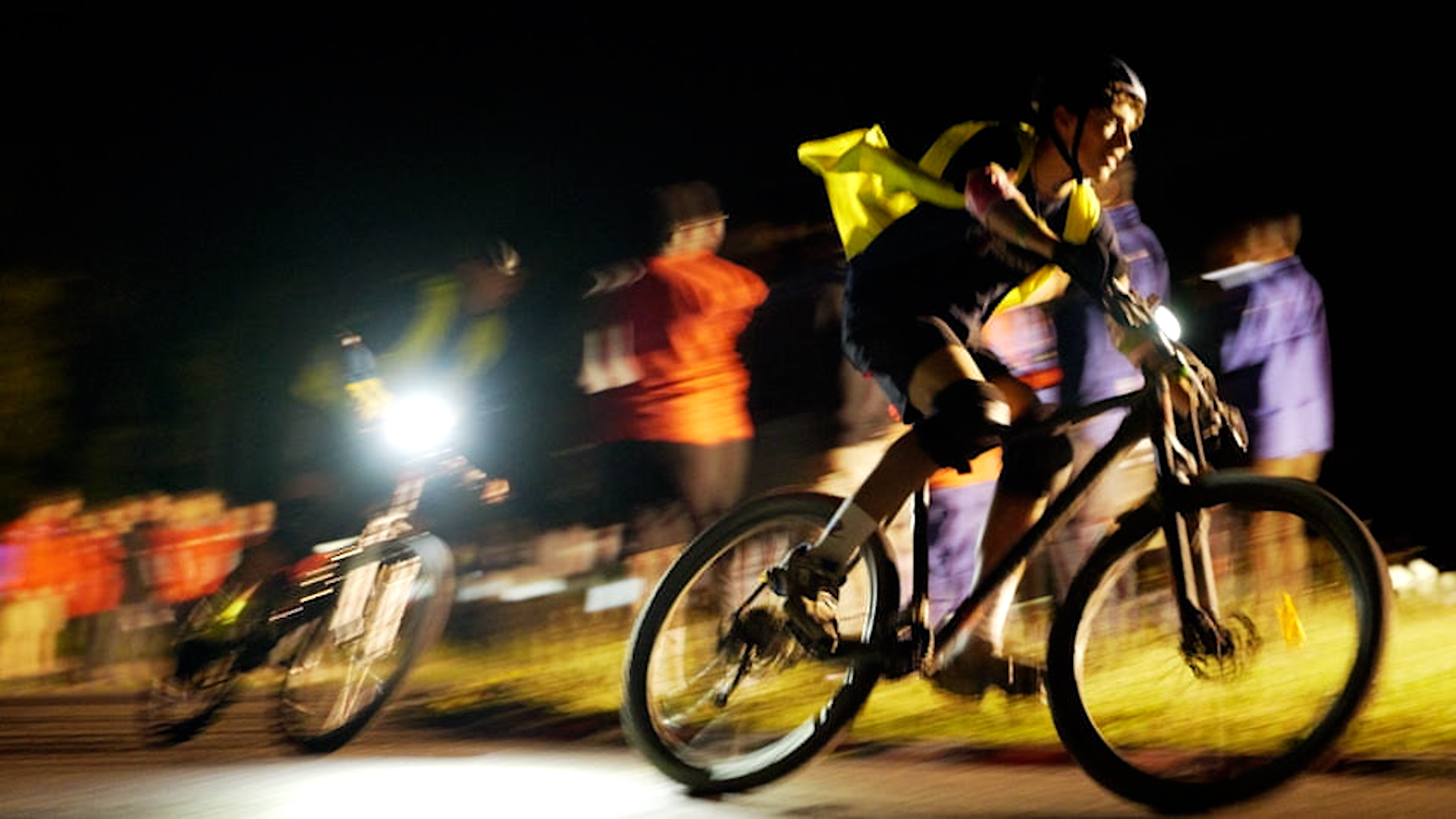 Deux cyclistes la nuit sous les projecteurs