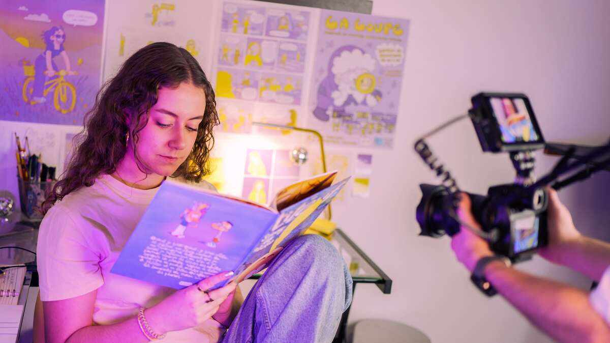 Cameraman filmant une personne lisant un bande dessinée.
