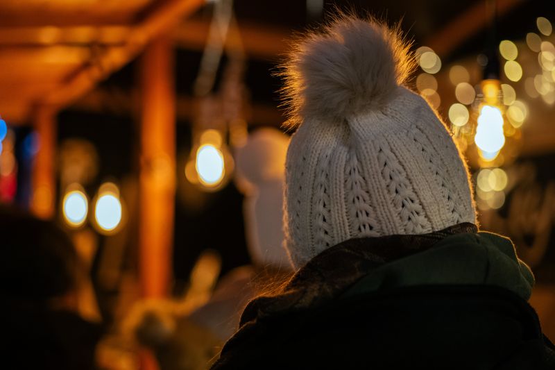 Une femme portant un bonnet devant un stand lumineux