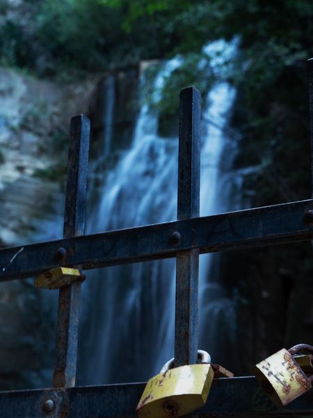 Deux cadenas accrochés à une grille devant une cascade
